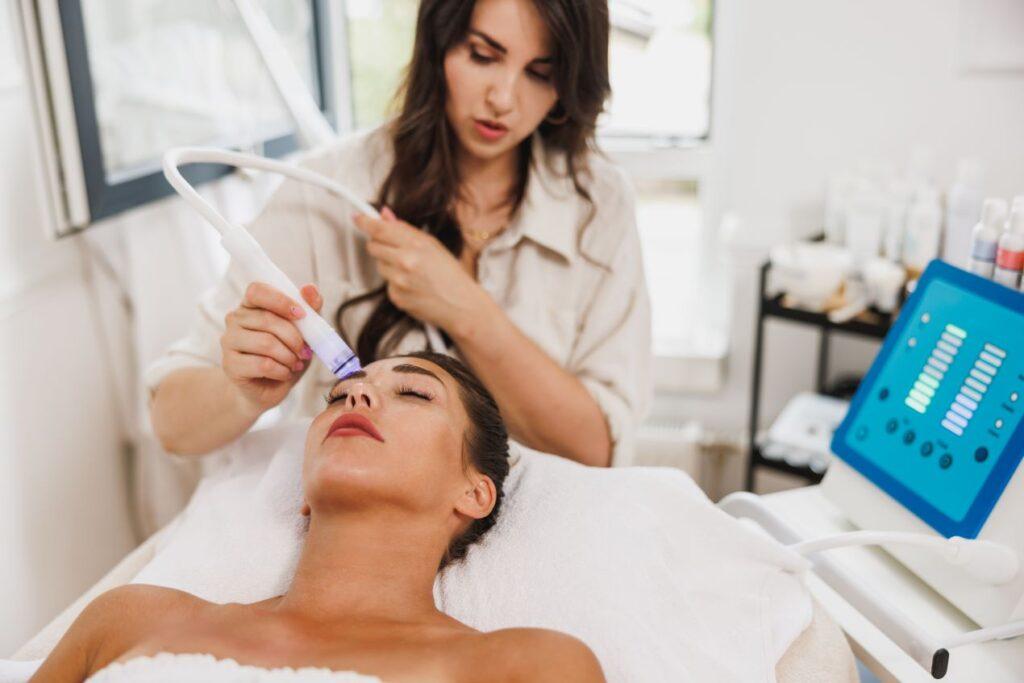 Kosmetikerin führt eine Hydrafacial Behandlung an einer Frau durch, um ihre Haut zu reinigen und zu revitalisieren