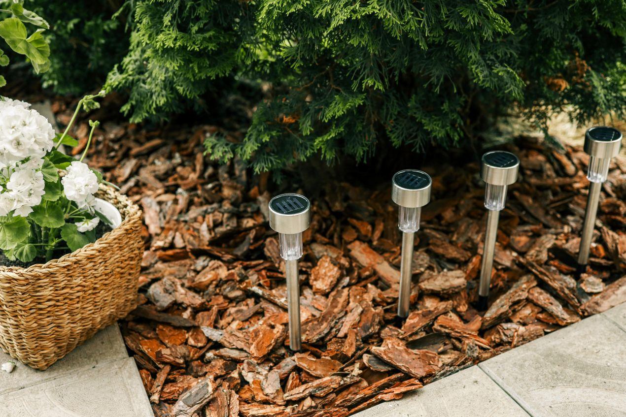 Solarleuchten stehen in einem nachhaltig gestalteten Garten, umgeben von Rindenmulch und Ziersteine, die für eine natürliche Bodenabdeckung sorgen.