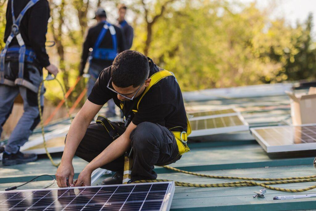 Arbeiter montiert Solarpanel auf Dach | Baumschule Jobs