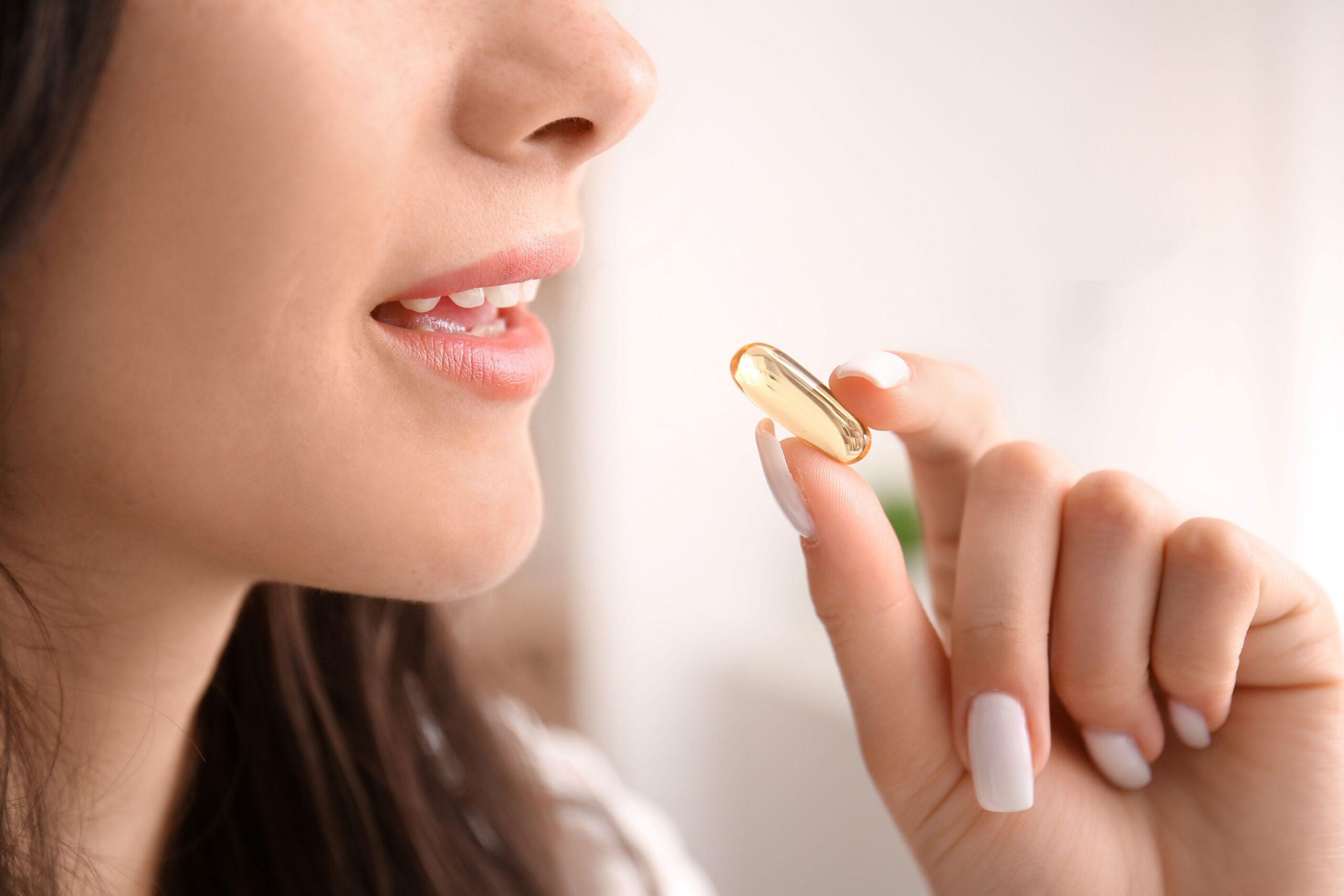 Frau hält eine Kapsel mit Omega-3 Algenöl vor dem Mund – pflanzliche Alternative mit klarer Wirkung